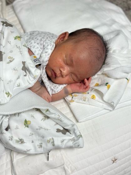 A baby sleeping peacefully in a cool, air-conditioned room, wearing a thin summer bodysuit