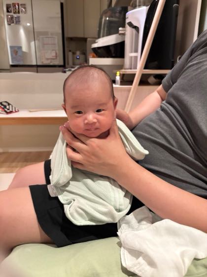 A baby resting comfortably in a parent's arms in a cool indoor space