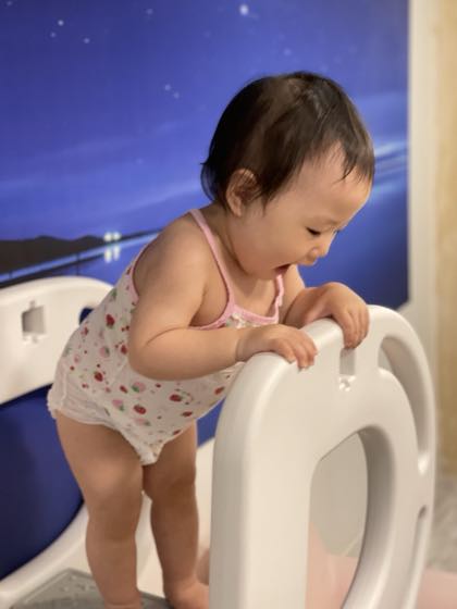 유아용 흰 의자를 붙잡고 서 있는 아기