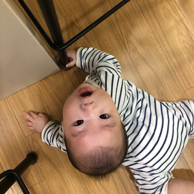 ふかふかの寝具がない、かたく平らな木の床に仰向けで寝て上を見ている赤ちゃん