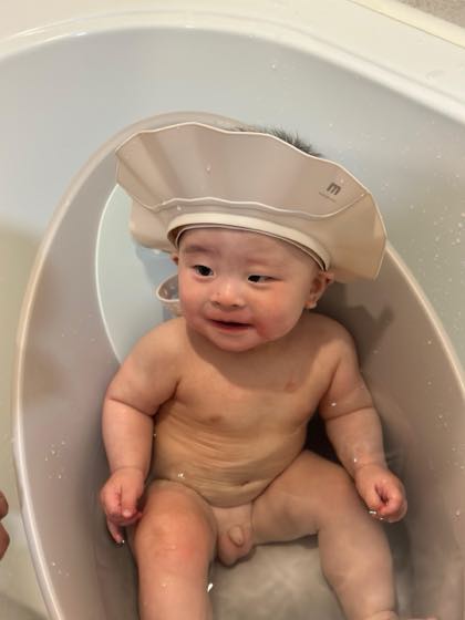 A baby sitting comfortably in a baby tub during a bath