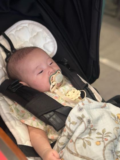 ベビーカーに座っておしゃぶりをくわえる夏の赤ちゃん