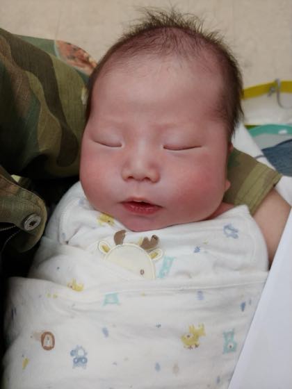 おくるみに包まれて昼寝をする新生児