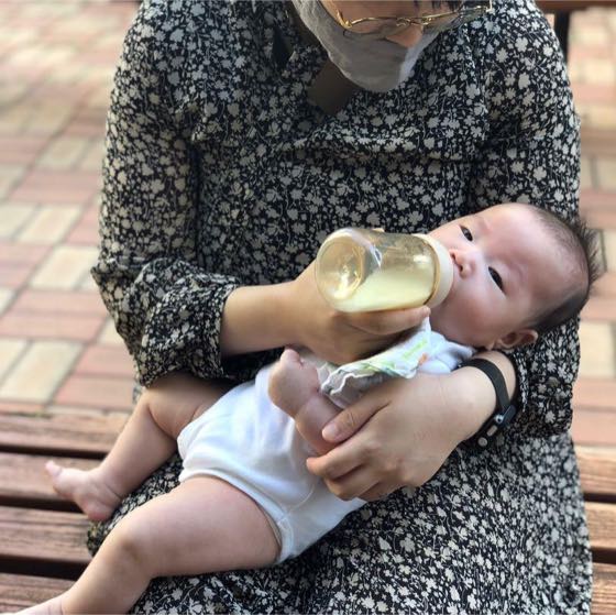 부모 품에 안겨 젖병으로 수유하는 아기