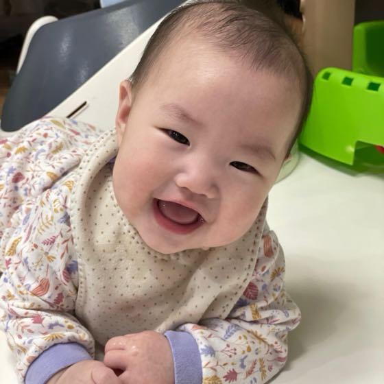 ハイチェアに座ってにっこり笑う健康な赤ちゃん
