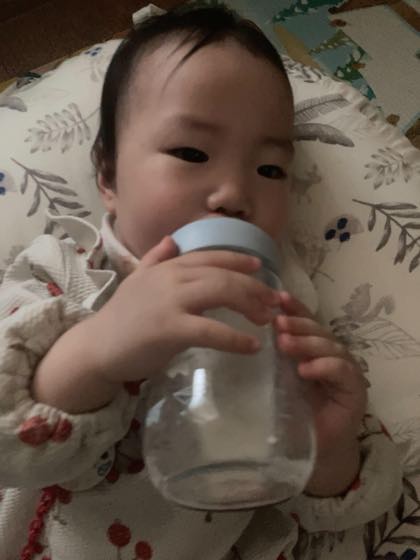 横になって哺乳びんでミルクを飲む赤ちゃん
