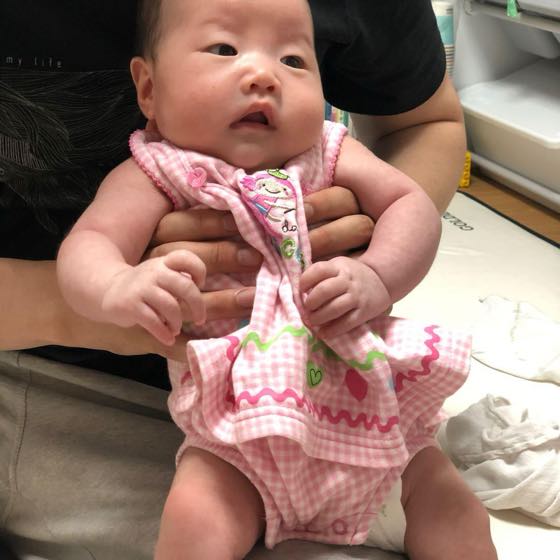 大人の両手で支えて抱いた小さな赤ちゃんの様子を見守る親