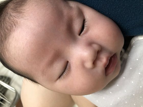 A baby asleep in an adult's arms with the head turned to the side