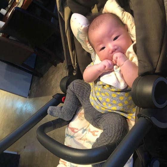 A baby dressed in long sleeves, sitting in a stroller
